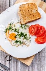 Fried eggs on a platter served with parsley and tomatoes.