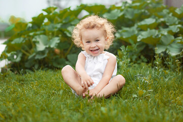 Adorable laughing little girl with long blond curly hair