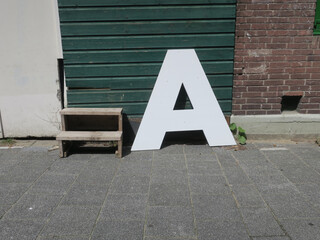 letter A standing on the sidewalk leaning against a green wooden door