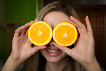 Portrait of a beautiful girl with orange slices in her hands .