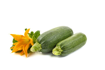 two fresh zucchini with green leaves and a flower isolated on a white background