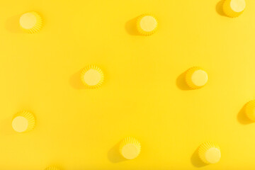 Trendy pattern made with yellow cap on bright yellow background. Minimal concept. Flat lay, copy space, top view.
