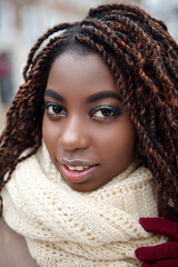 African girl smiling with makeup and in a beige scarf, close-up in a winter day.
