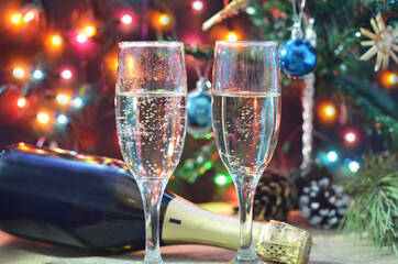 two glasses of champagne on the background of champagne. Christmas tree with Christmas lights. New Year and Christmas. Gift boxes tied with bows
