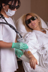 Laser hair removal with a modern device on the arm and leg of a young and beautiful woman. Hair removal by laser surgery