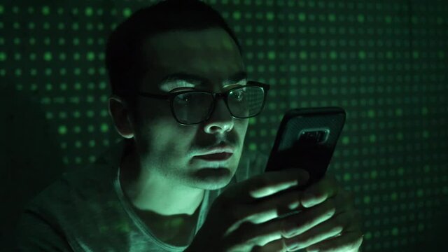 Hacker using his phone to hack accounts. Matrix like background animated.