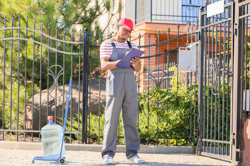 African-American delivery man with bottle of water outdoors