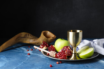 Sacramental goblet with wine, apple and pomegranate on table. Rosh Hashanah (Jewish New Year)...