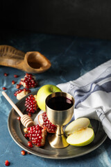 Sacramental goblet with wine, apple and pomegranate on table. Rosh Hashanah (Jewish New Year) celebration