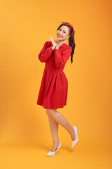 Beautiful young Asian woman with red dress over orange background. Full length