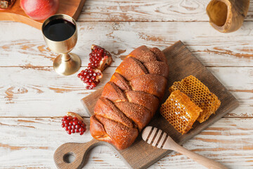 Challah with honey, pomegranate and sacramental goblet with wine on table. Rosh Hashanah (Jewish New Year) celebration