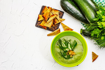Green zucchini cream soup. Healthy vegan (vegetarian) food, crispy toast, sesame seeds, whole ripe fruits, fresh greens