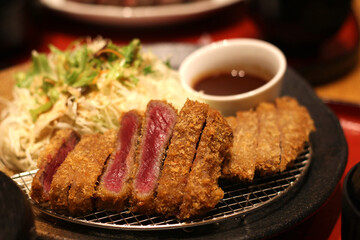 Close up of a plate of delicious fried steak served with vegetable salad and sauce, Osaka, Japan, soft focus
