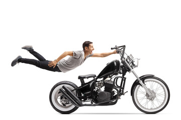 Young man flying and holding on to a chopper motorbike
