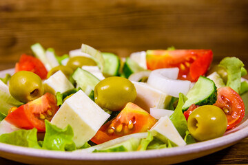 Ceramic plate with greek salad on wooden table