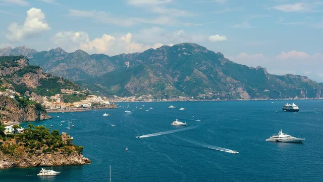 Slide right. Time lapse view from Conca dei Marini on Amalfi bay, Luxury boats traffic, fishing boats, tourist season. watercraft. Mountains and houses, buildings. Summer day in vacation. Italy