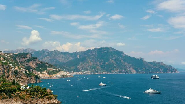 Slide up, Time lapse view from Conca dei Marini on Amalfi bay, Luxury boats traffic, ocean liner, fishing boats, tourist season. Mountains and houses, buildings. Summer day in vacation. Italy