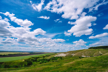 Fototapeta na wymiar Panorama a picturesque landscape with hills and green lawns and a blue sky with clouds