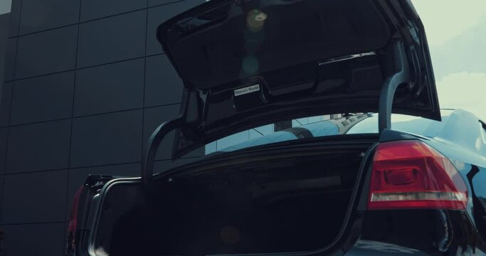 happy woman taking shopping bags from car trunk