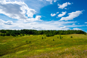 Panorama a picturesque landscape with hills and green lawns and a blue sky with clouds