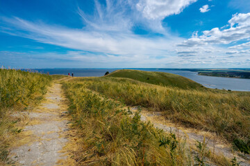 Panorama of the Russian picturesque landscape with hills and flower fields and blue sky with clouds on the background of the sea