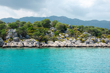 Naklejka premium Seascape. View from the water to Islands in the Mediterranean sea. Wild unspoilt nature of Turkey. Stone cliffs and mountains covered with green bushes and trees. Summer landscape from pleasure boat