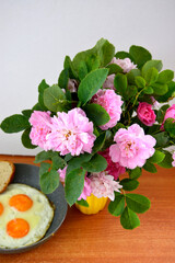 Pink peony flowers stand in a yellow vase. A bunch of flowers and fried eggs in a frying pan.