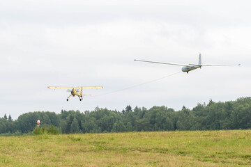 Obraz na płótnie Canvas towing a glider by plane. plane in the sky. the flight of the glider. airplane train, glider takeoff. Glider on a cable behind the plane in the sky. take-off of the plane from the field. aviation