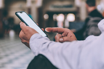 A man with a smartphone in his hands sits at the station.