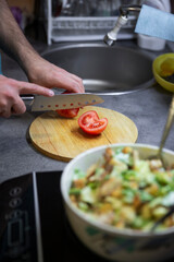 Preparation of juicy salad with chicken, iceberg lettuce and tomatoes.