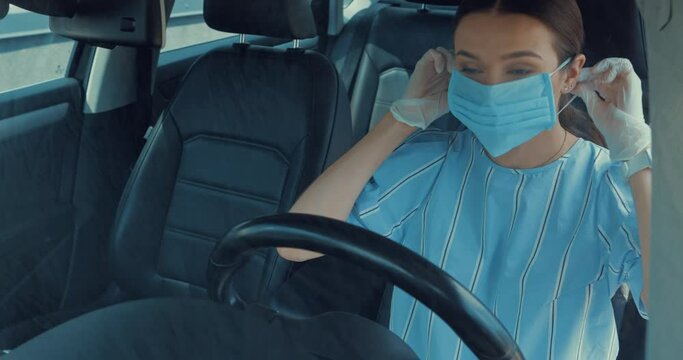 young woman in latex gloves putting on medical mask while sitting in car