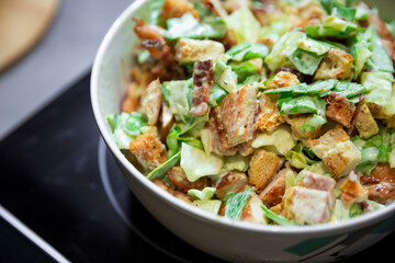 Preparation of juicy salad with chicken, iceberg lettuce and tomatoes.