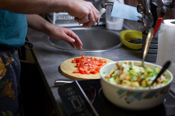 Preparation of juicy salad with chicken, iceberg lettuce and tomatoes.