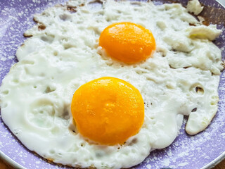 Close-up fried eggs in pink fryin pan