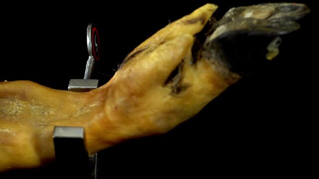 Panning left showing the detail of the hoof of a ham pig leg where a selective focus. black and yellow orange meat colors shinning