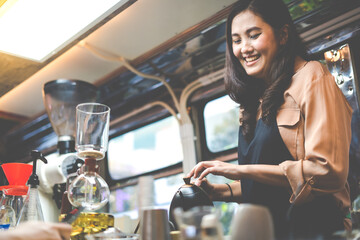 Young Asian woman pouring milk into coffee making late coffee. Professional barista preparing coffee on counter