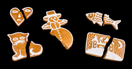 Set of broken decorated Xmas gingerbreads isolated on black background. Close-up of damaged sweet holiday cookies. Separated house, heart with sad emote or snowman piece. Cracked chips of cat or fish.