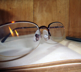 Lentes con reflejo de llamas de vela sobre un libro