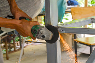 The technician uses a electric grinding wheel on steel structure Sparks  the workpiece to be completed.