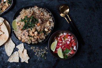 Indian rice and mushroom pilaf along with salad and popadum crackers on dark backround, copy space