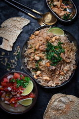 Indian rice and mushroom pilaf along with salad and popadum crackers on dark backround, copy space