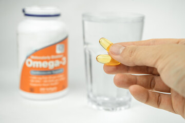 omega 3 fish oil big gel capsules and glass of water, healthcare, vitamins