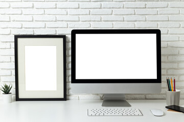 mockup computer with blank white screen and empty Poster frame with workspace and office supplies on desk