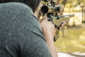 Military sniper with his precising sniper rifle aiming through scope and shooting in the shooting...