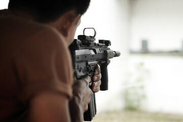 Military shooter with his precising assault rifle aiming and shooting target in the range