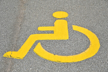 Yellow disabled sign on the asphalt of the street