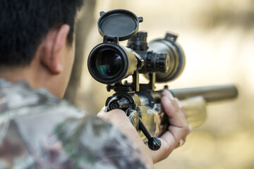 Military sniper with his precising sniper rifle aiming through scope and shooting in the shooting range 