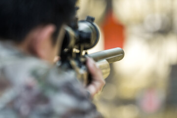 Military sniper with his precising sniper rifle aiming through scope and shooting in the shooting...