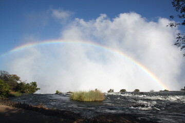 Beautiful rainbow over the famous Victoria Falls on the Zambezi River in South Africa. At the end...