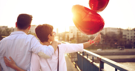 smiling couple in love with balloons on sunset